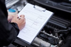 A man taking notes on a clipboard for an auto repair shop.